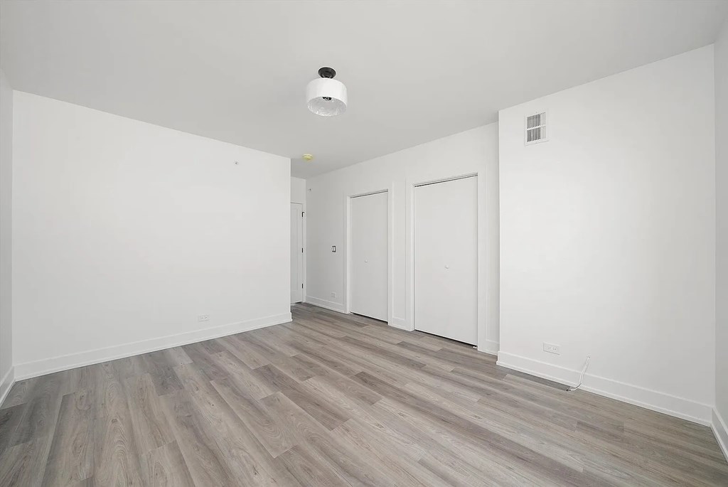 A room with a white ceiling and wooden flooring with two white doors.