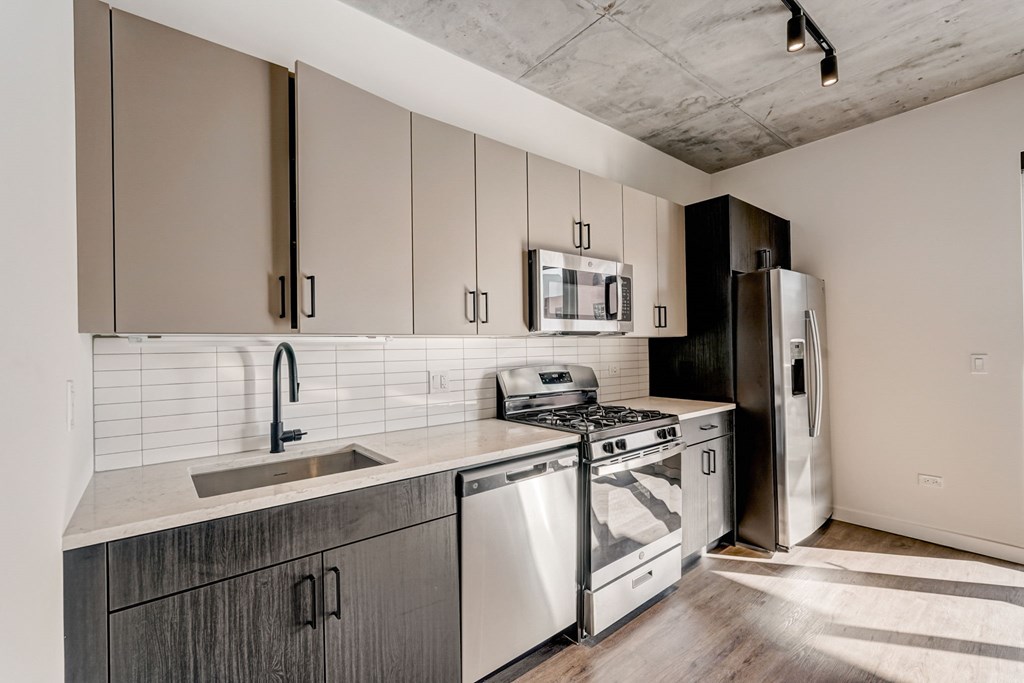 A kitchen with a stainless steel refrigerator, microwave, and oven.