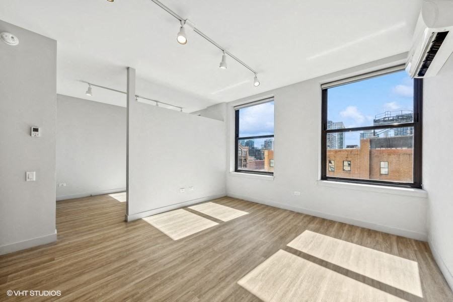an empty living room with two windows and wood floors