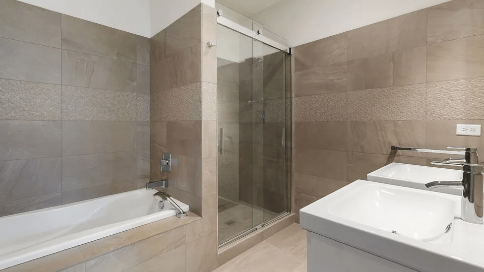 A bathroom with a white sink, a bathtub, and a glass shower door.
