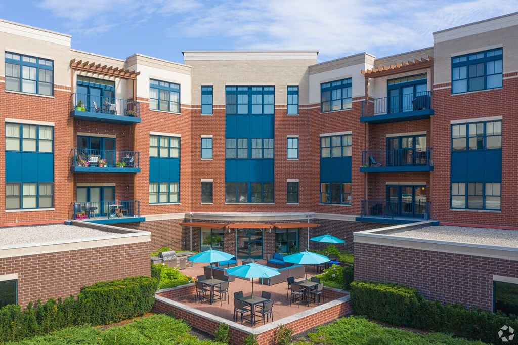 A large building with a patio and blue umbrellas.