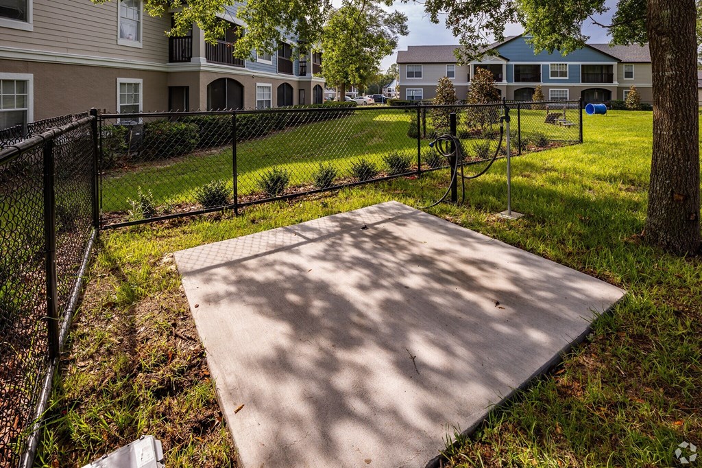 A concrete slab in the foreground with a black fence and grassy area in the background.