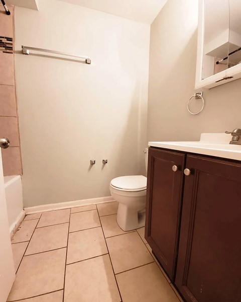 A white toilet sits in a bathroom with brown cabinets.