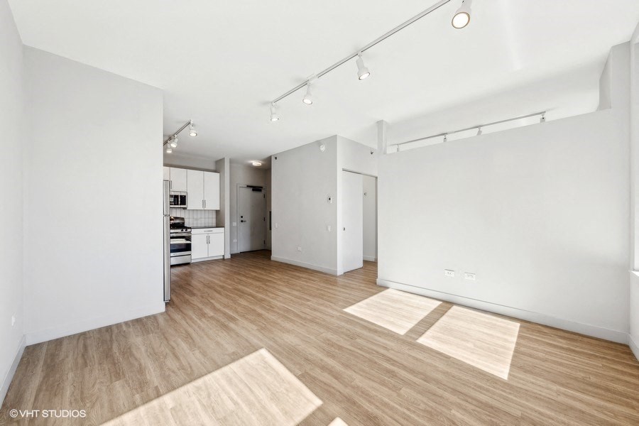 a living room and kitchen with white walls and wood floors