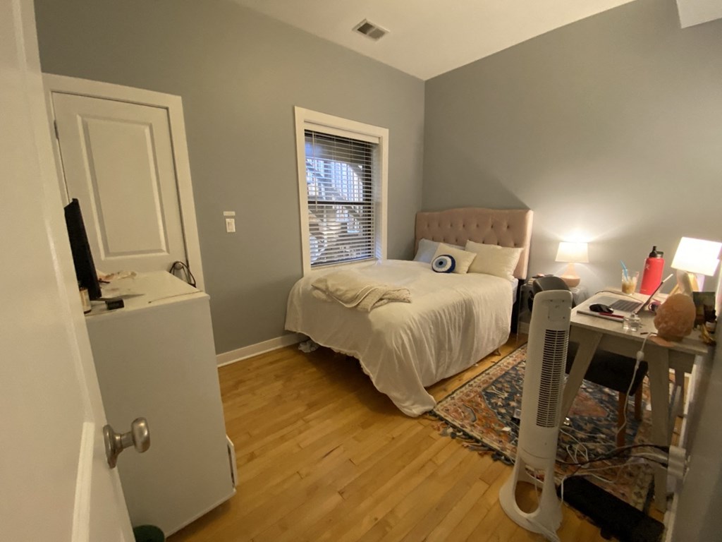 a bedroom with a bed and a desk and a window