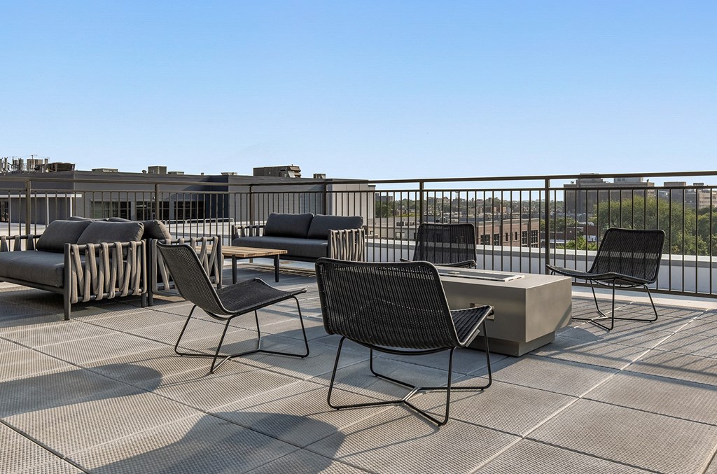 a rooftop patio with chairs and tables and a fire pit