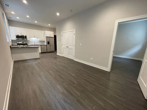 A spacious kitchen with white cabinets and a dark wood floor.