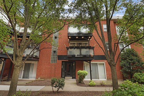 A red brick building with a balcony and a black door.