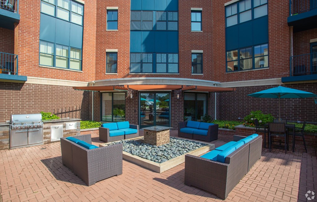 A patio area with a table and chairs and a blue umbrella.
