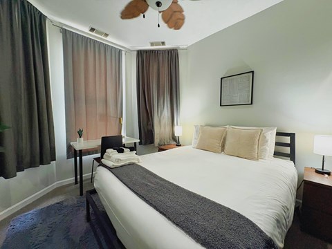 A bedroom with a large bed and a ceiling fan.