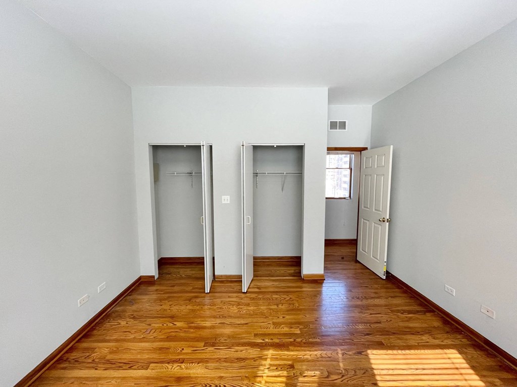 a room with wood floors and grey walls and three closets