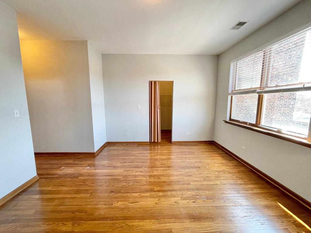 an empty living room with wood floors and a large window