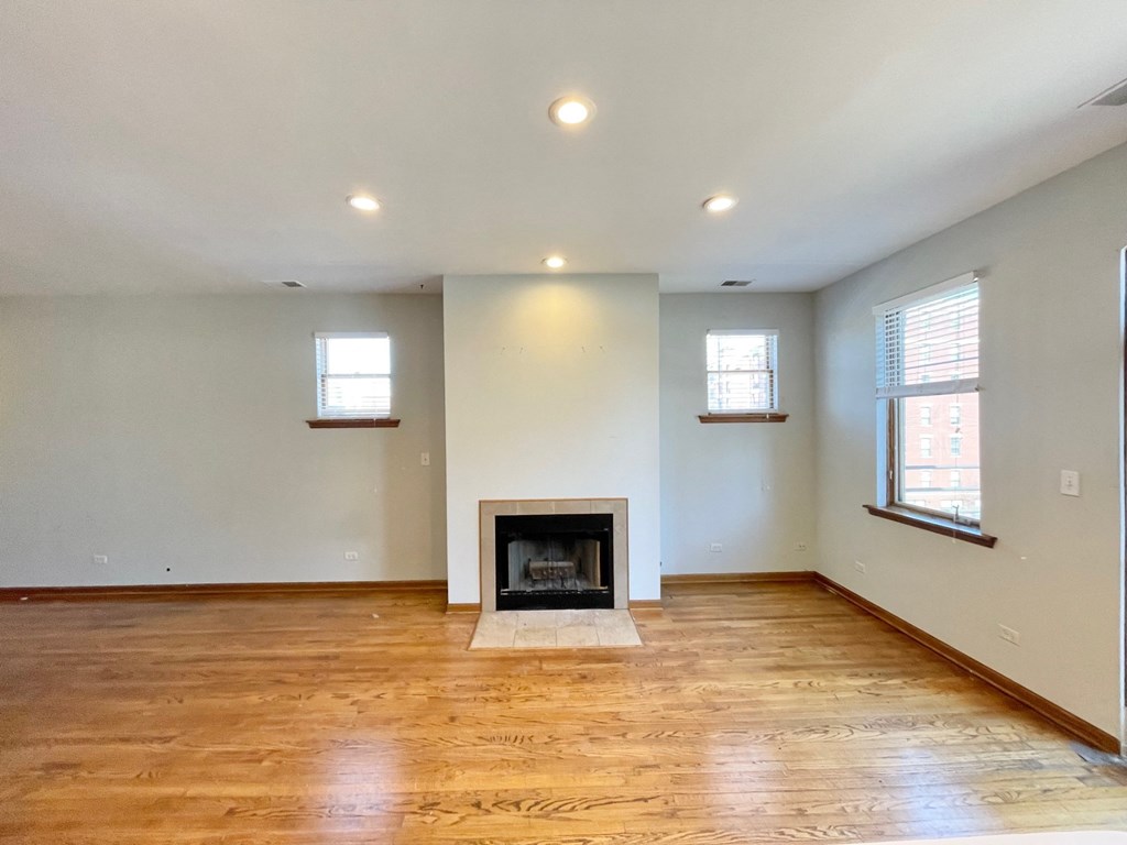 an empty living room with a fireplace and wooden floors