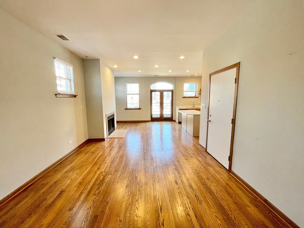 an empty living room with a hard wood floor and a kitchen