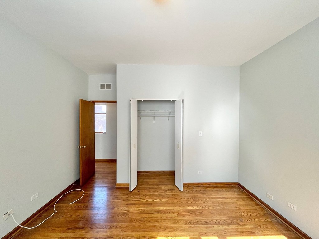 an empty room with wood floors and white walls and a closet