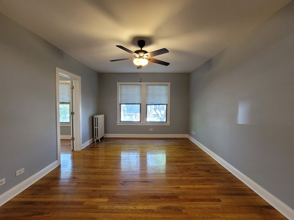 an empty living room with a ceiling fan and a window
