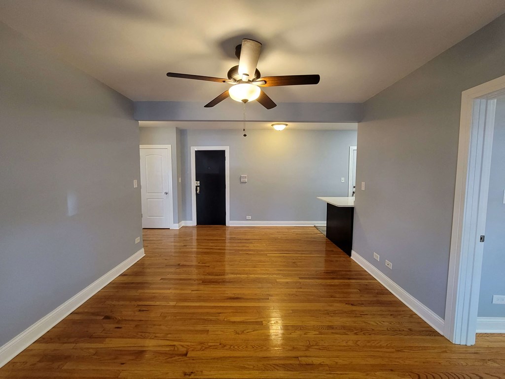 a empty living room with a ceiling fan and wood floors