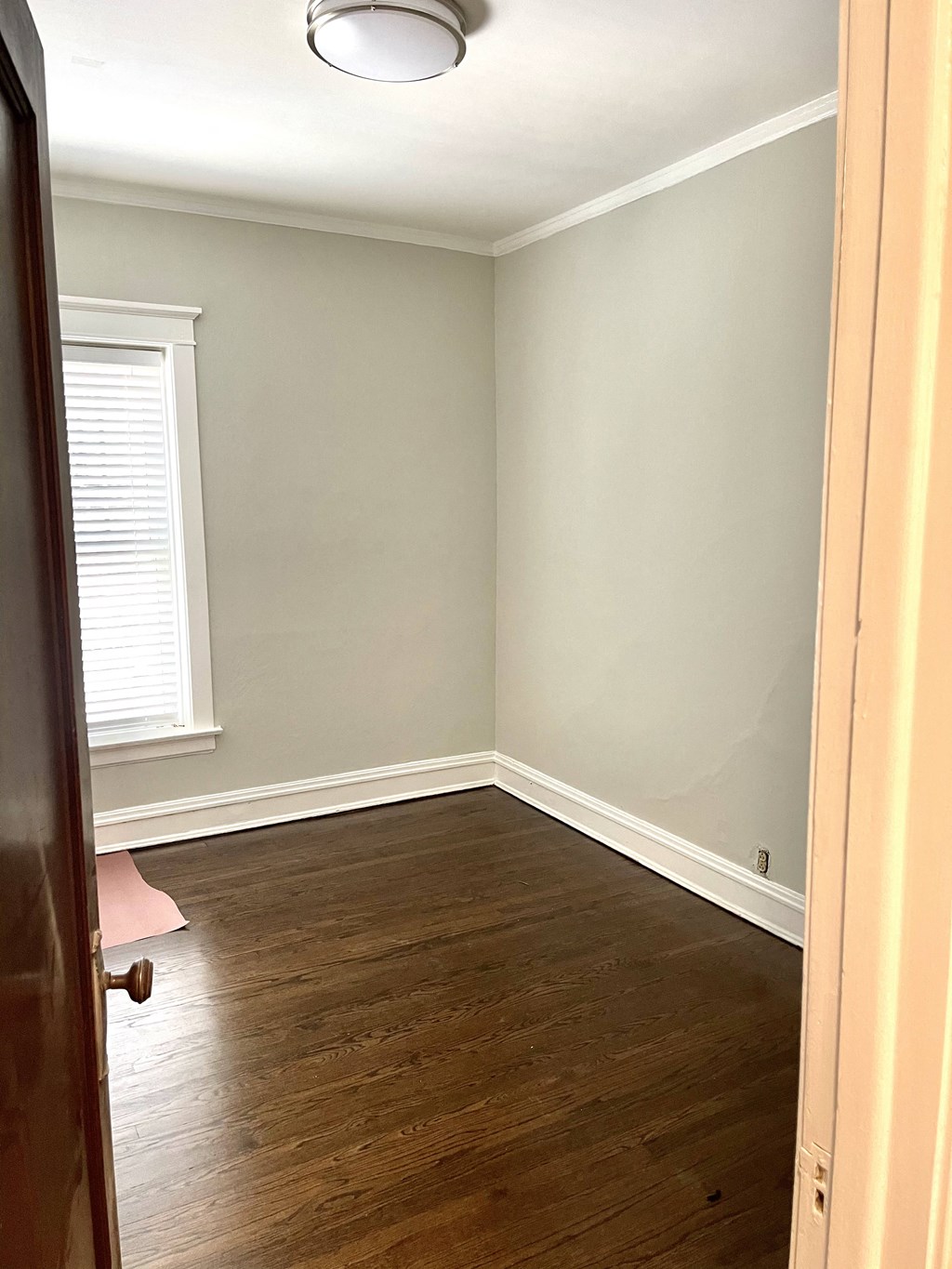 an empty room with wood flooring and a window and a door