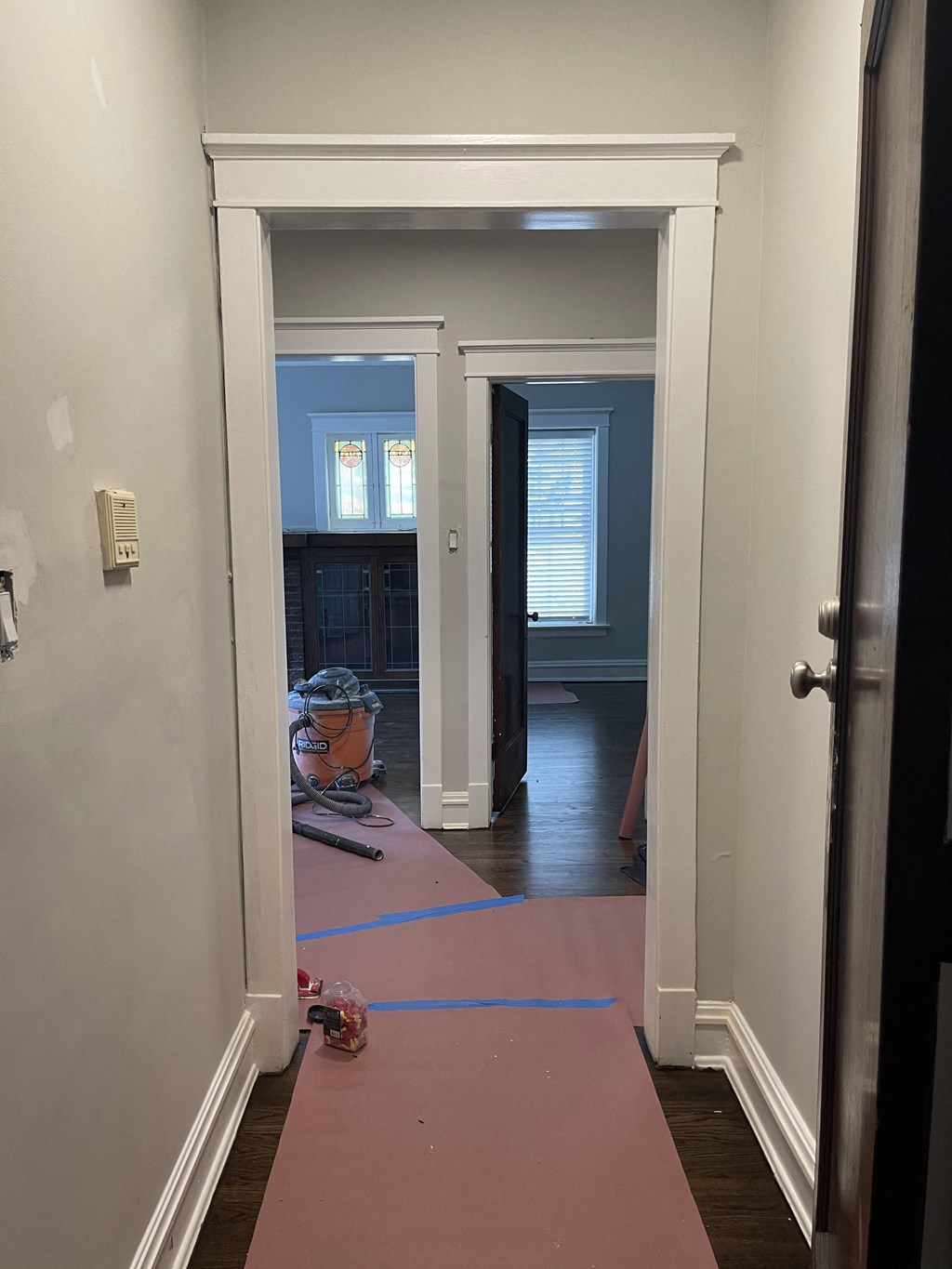 a room with a pink rug on the floor and a hallway with a door open