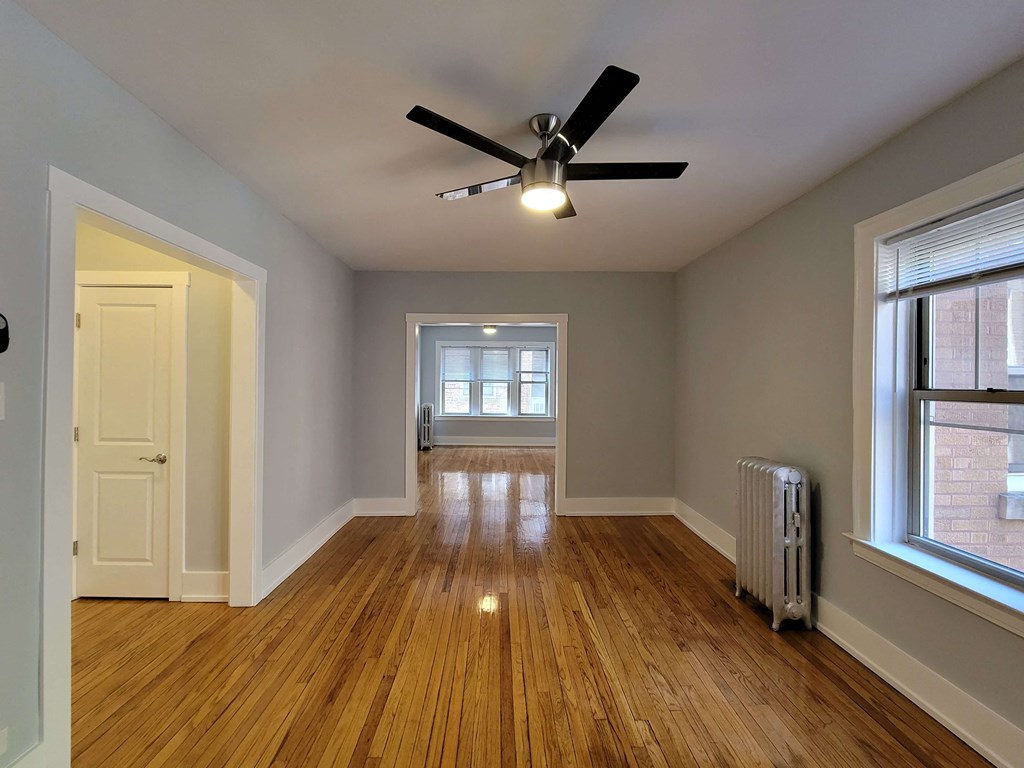 an empty living room with wood floors and a ceiling fan