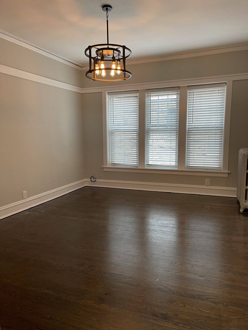 an empty living room with a large window and a chandelier