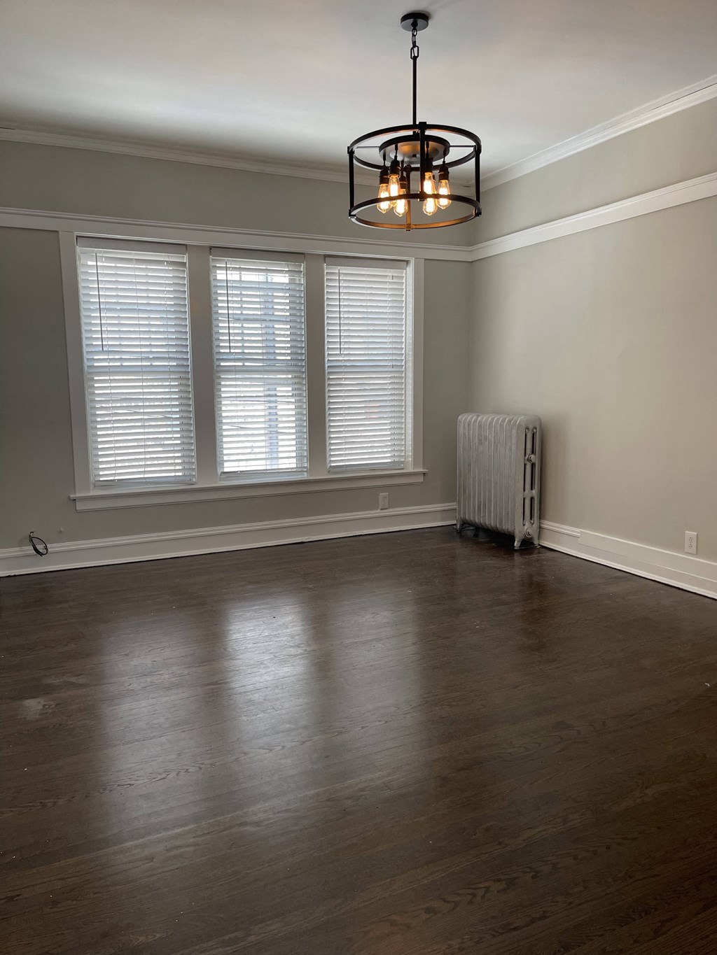 an empty living room with wood floors and a large window