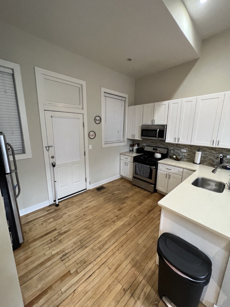 an empty kitchen with white cabinets and a wood floor