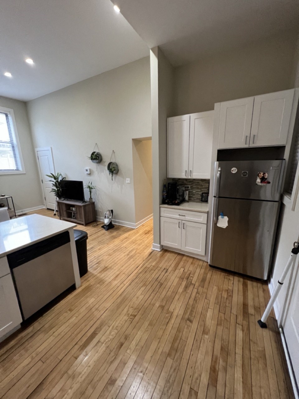 a kitchen with a wooden floor and a stainless steel refrigerator