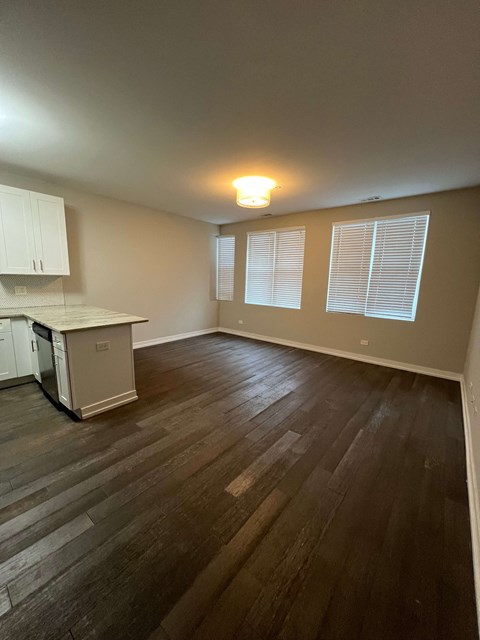 an empty living room with a kitchen in the background