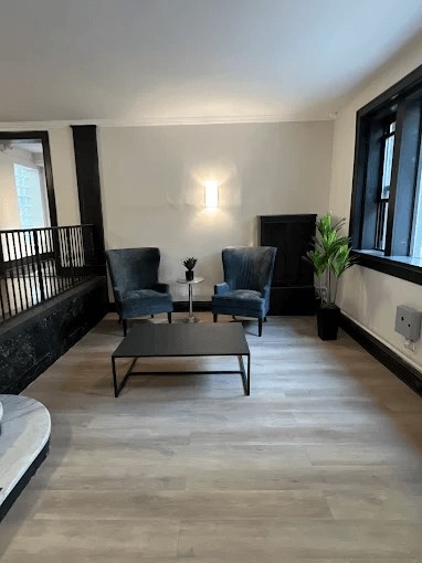 A living room with a black coffee table and two blue chairs.