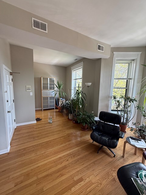A living room with a black chair and wooden floors.
