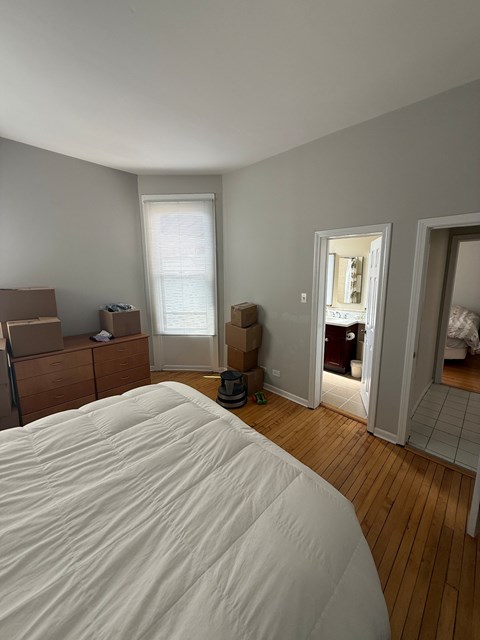 A bedroom with a bed in the foreground and boxes and a mirror in the background.