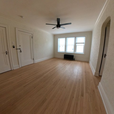A room with wooden flooring and a ceiling fan.