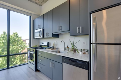 A modern kitchen with a stainless steel refrigerator and grey cabinets.