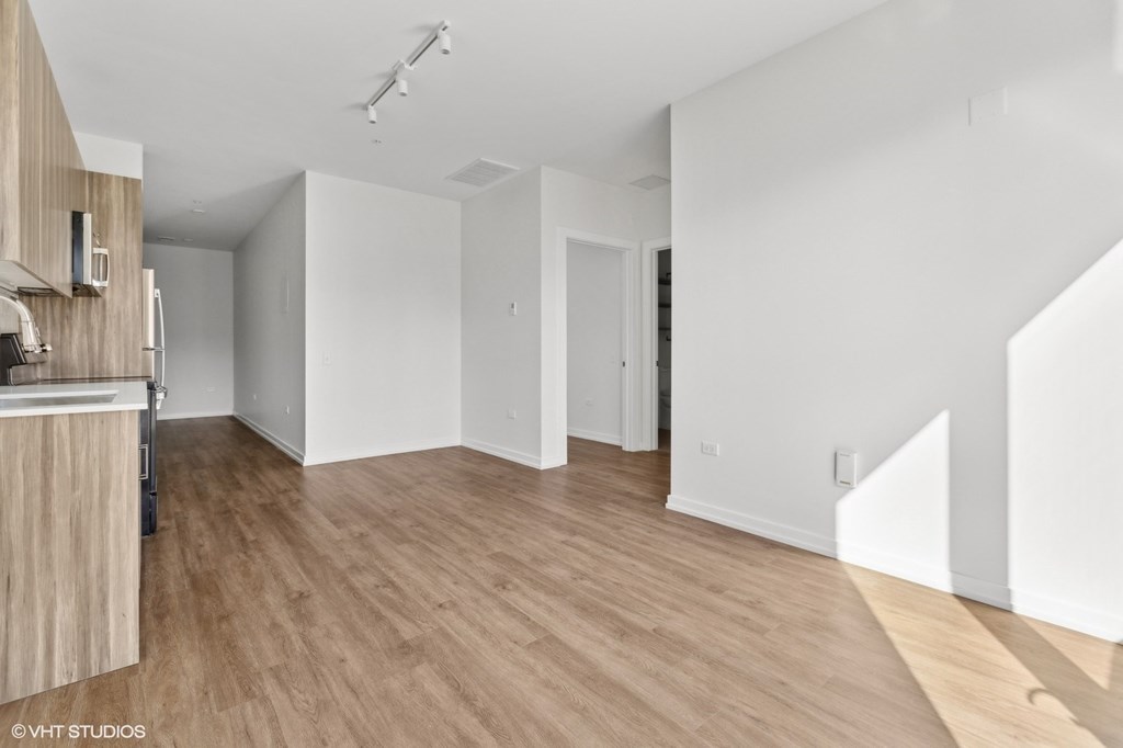 A spacious room with wooden flooring and white walls.