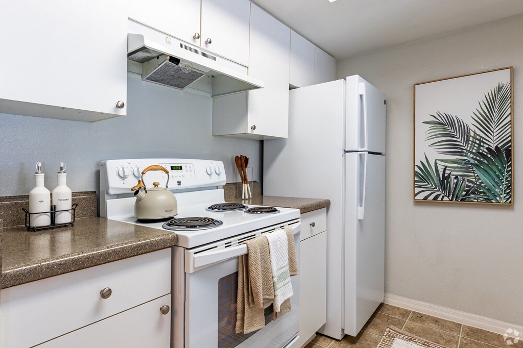 A kitchen with white appliances and a painting on the wall.