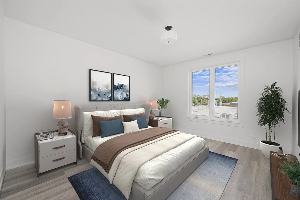 A well-lit bedroom with a large bed and a potted plant.