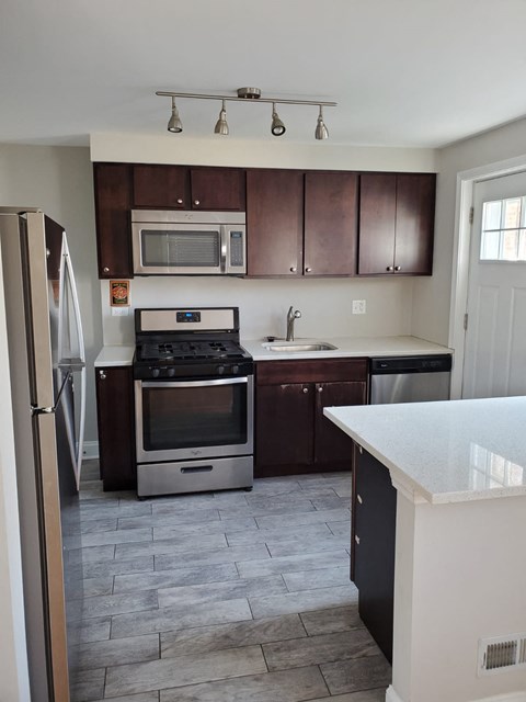 A kitchen with a refrigerator, oven, microwave, and sink.