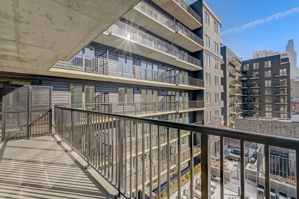 A balcony with a metal railing overlooks a cityscape.