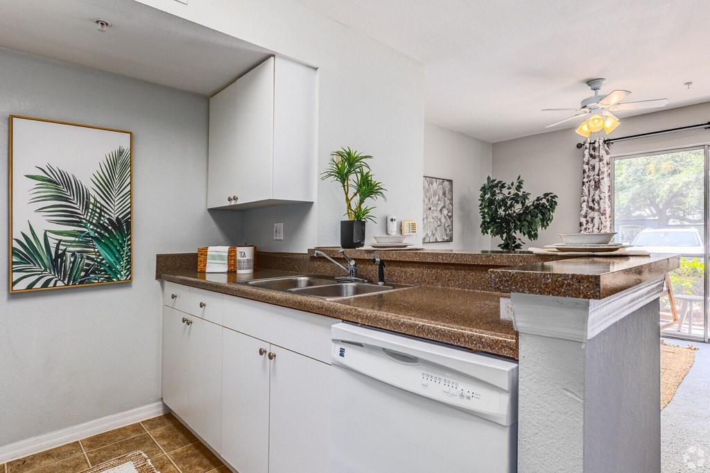A kitchen with white cabinets and a brown countertop.