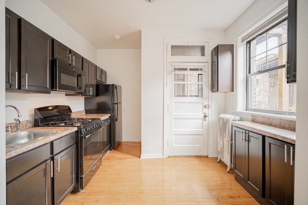a kitchen with stainless steel appliances and black cabinets and a white door