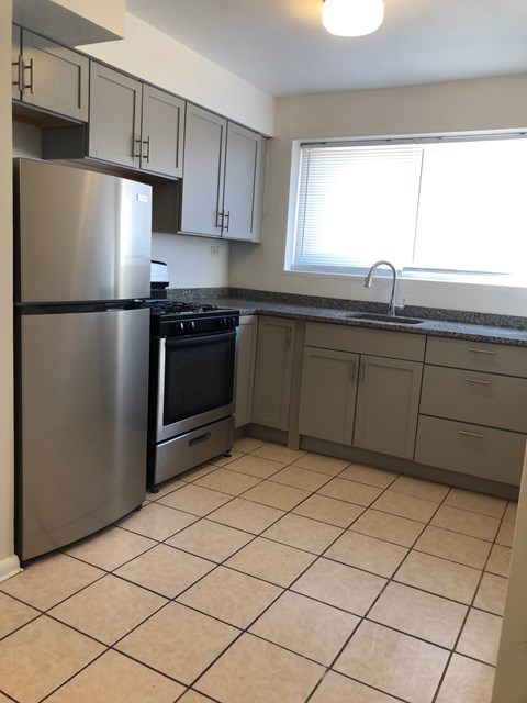 A kitchen with a stainless steel refrigerator and a black stove top oven.