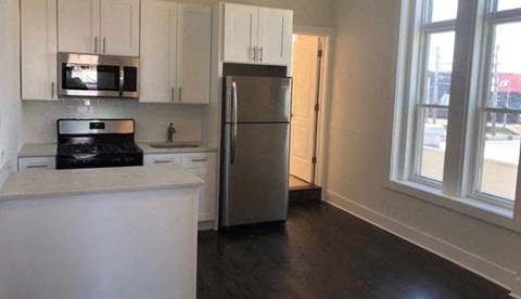 A kitchen with white cabinets and a stainless steel refrigerator.