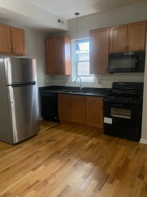 a kitchen with wooden floors and a stainless steel refrigerator