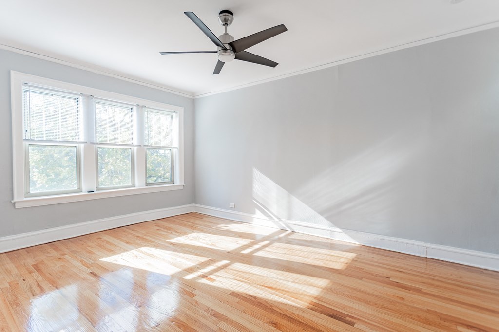 an empty room with wooden floors and a ceiling fan