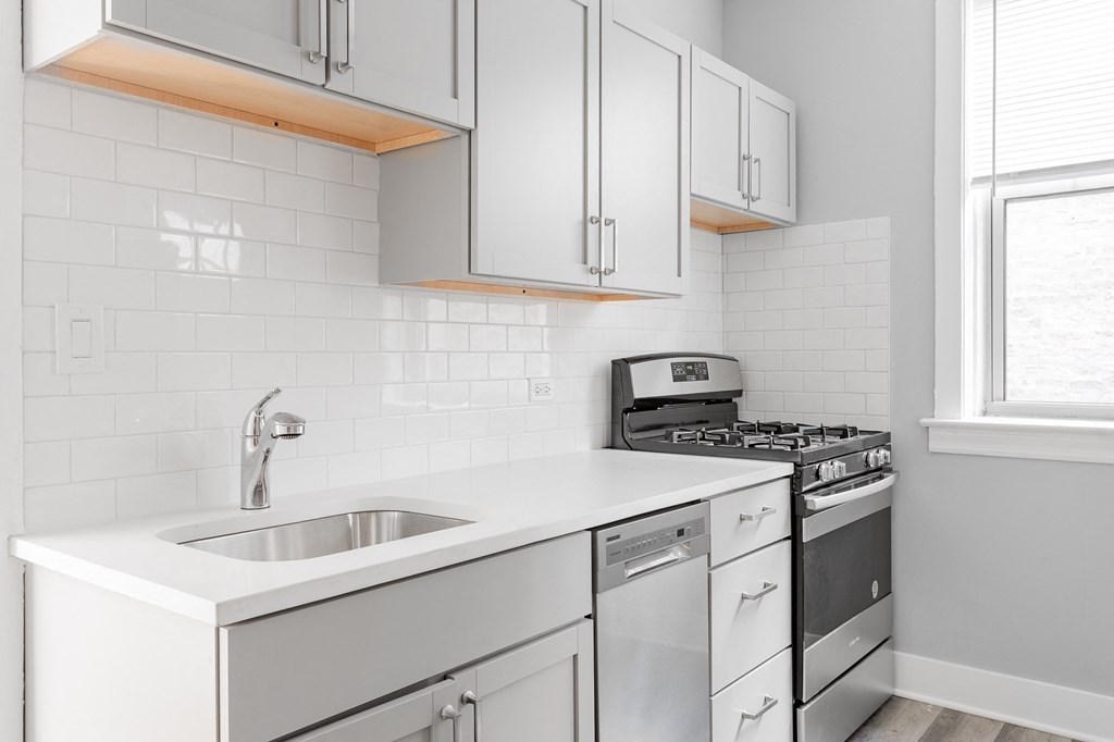 a kitchen with white cabinets and a sink and a stove