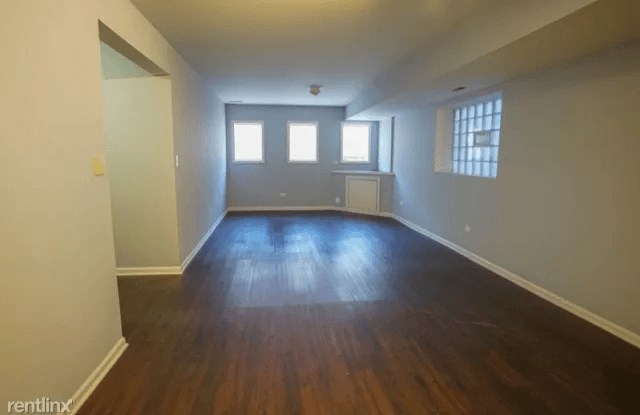 an empty living room with wooden floors and a window