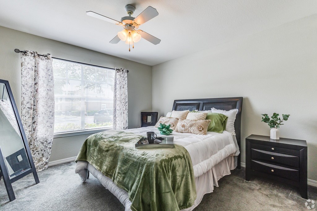 A bedroom with a bed, nightstand, and a ceiling fan.