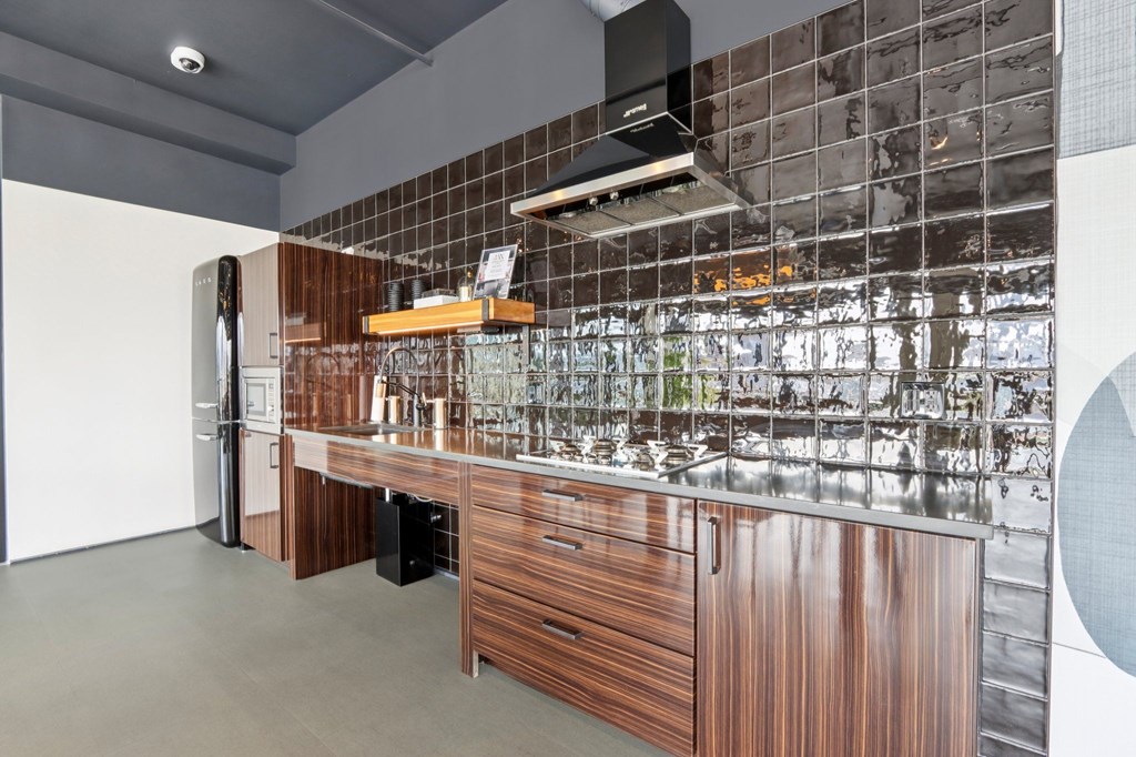 A modern kitchen with a wooden counter and a black and white tiled wall.