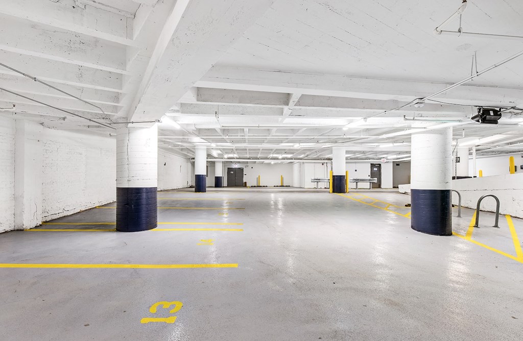a large parking garage with white pillars and a concrete floor